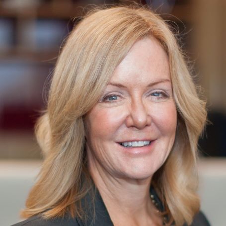 Ms Lisa Paul AO PSM head shot of smiling lady with blonde sholder length hair wearing a grey business jacket and grey top with a silver necklace