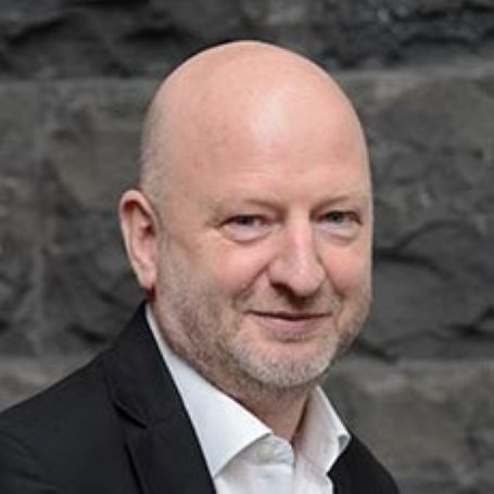 Professor Stephen Lamb head shot of bald man smiling wearing a white coloured shirt and black suit jacket.