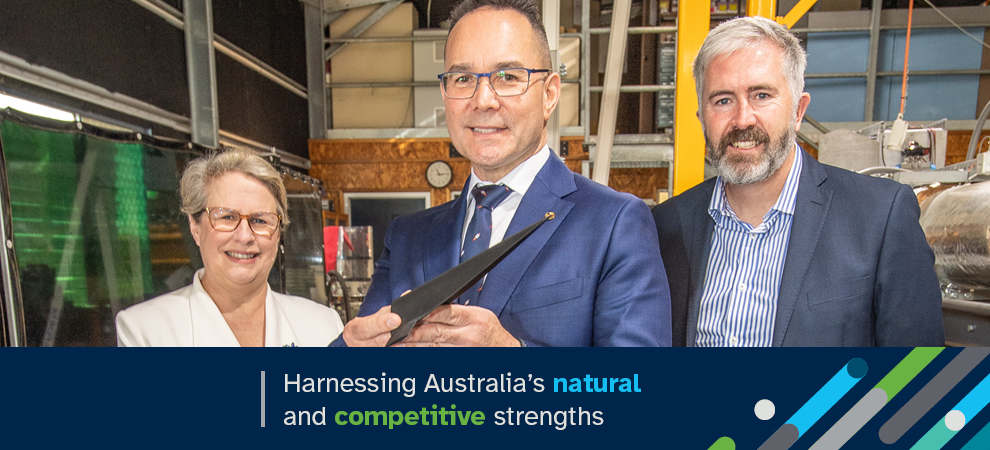 Three people standing in a warehouse or factory and dressed in business attire. Includes the words: Harnessing Australia’s natural and competitive strengths.