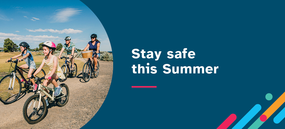 Stay safe this summer. In the background, there are four people riding bicycles together: a man, a woman and two girls.