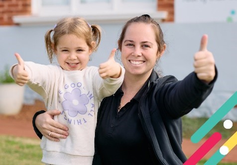 Young girl and woman sticking their thumbs up in an embrace