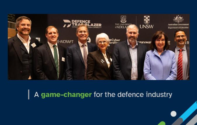 Photograph of seven people dressed in business attire and smiling at an event relating to Defence Trailblazer, with the words: A game-changer for the defence industry.